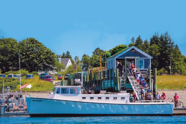 Passengers boarding a white boat at a wooden dock on a sunny day.