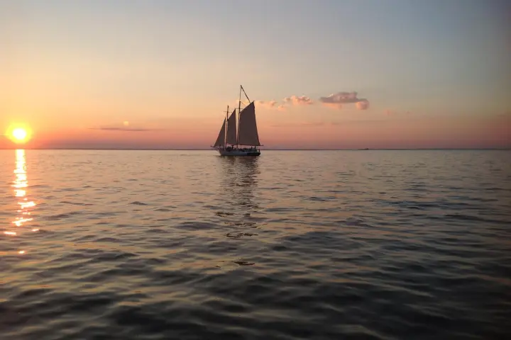 a sunset behind a boat on a body of water