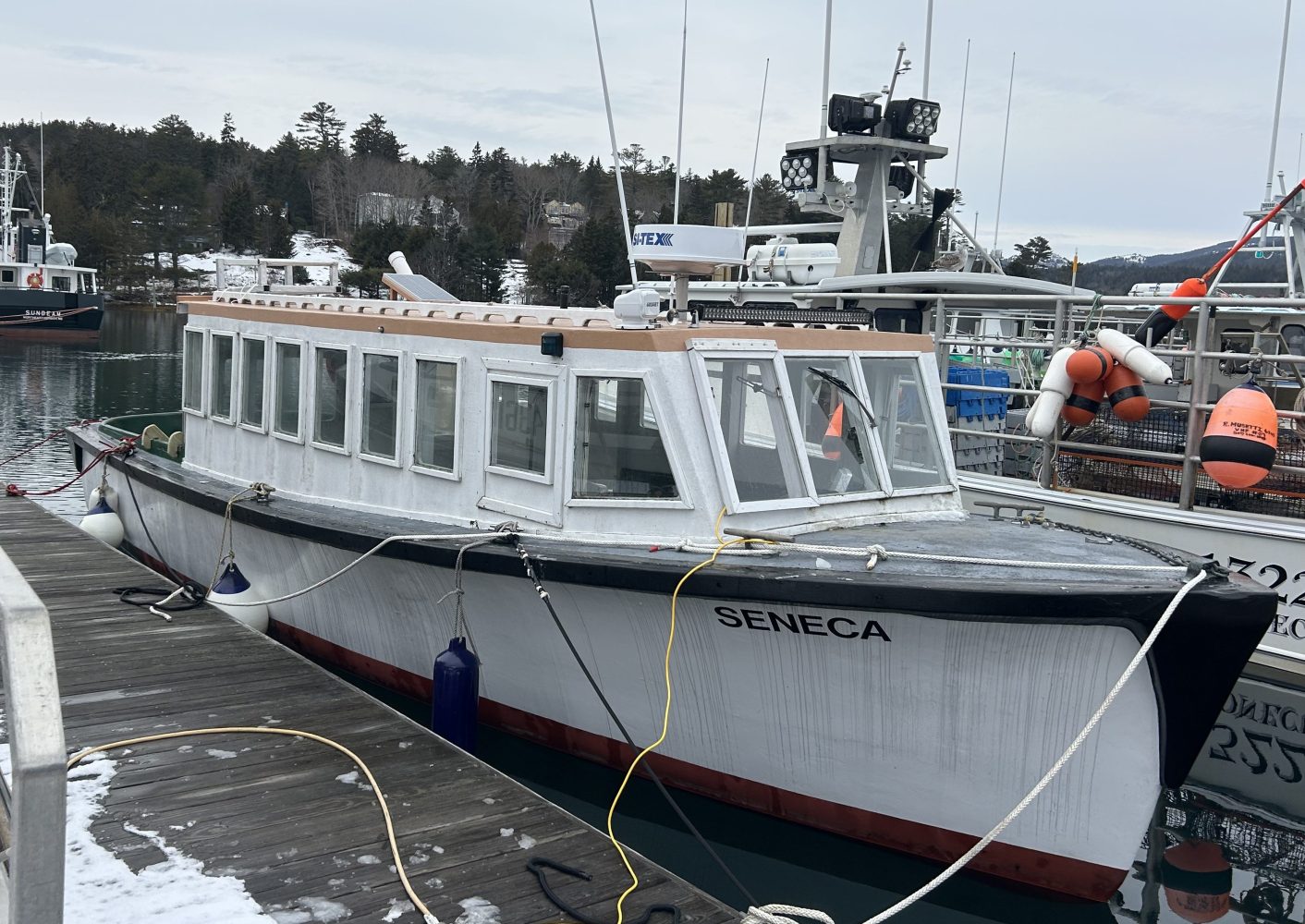 Docked boat named Seneca with cabins, surrounded by other boats.