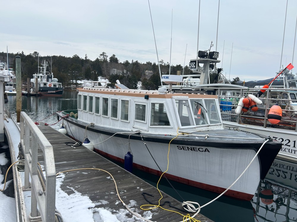 Docked boat named Seneca with cabins, surrounded by other boats.