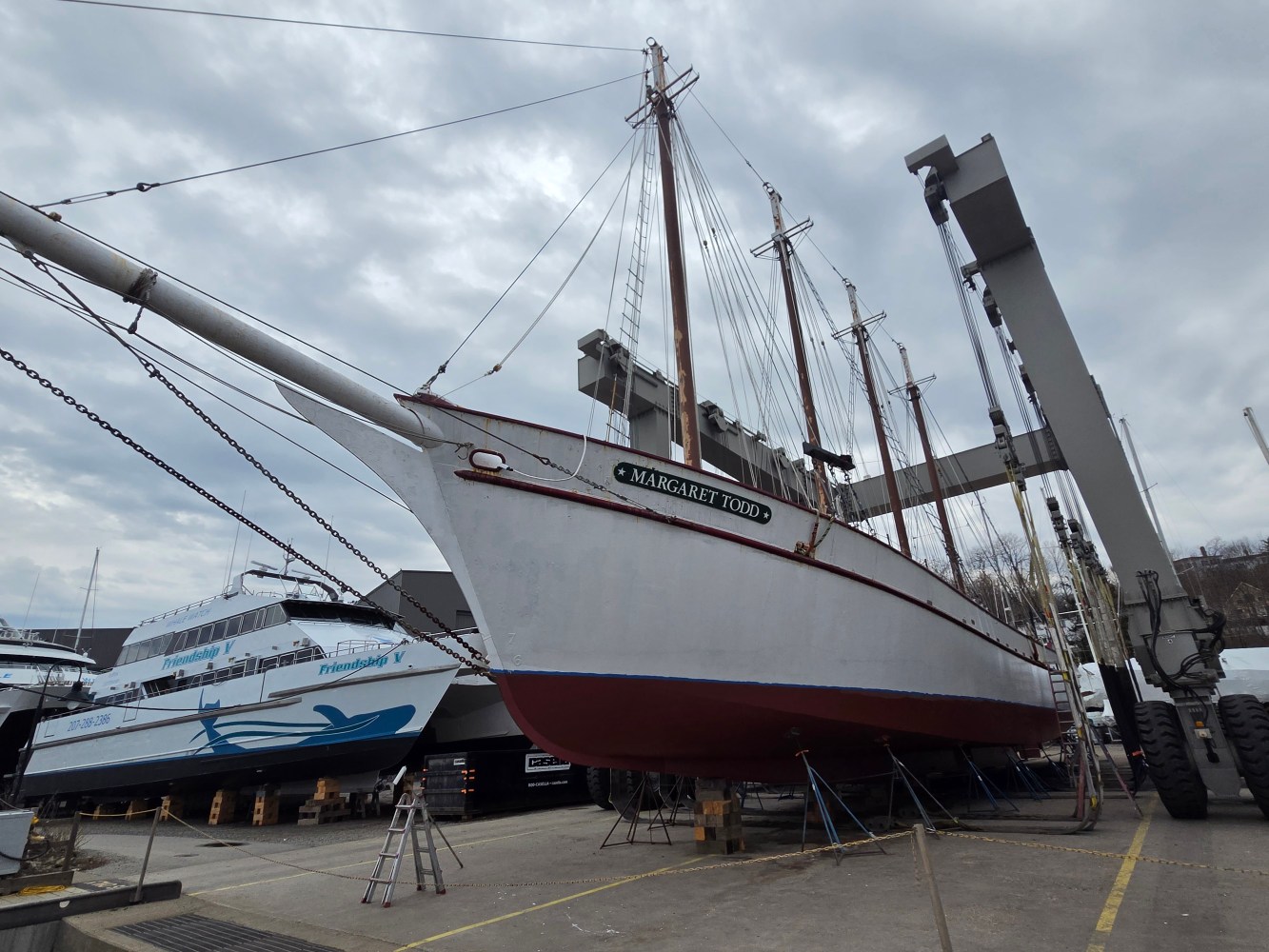 Large white sailboat named 'Margaret Todd' on dry dock beside cranes.