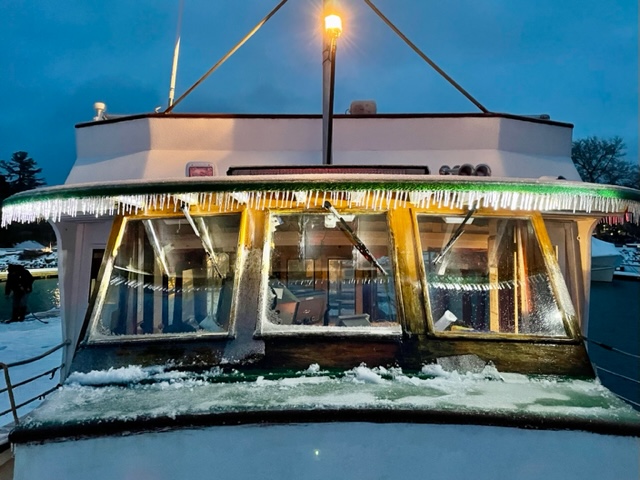 Boat cabin with icicles hanging from the roof, covered in snow.