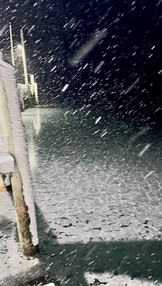 Snowstorm at night with snow-covered walkway and railing.