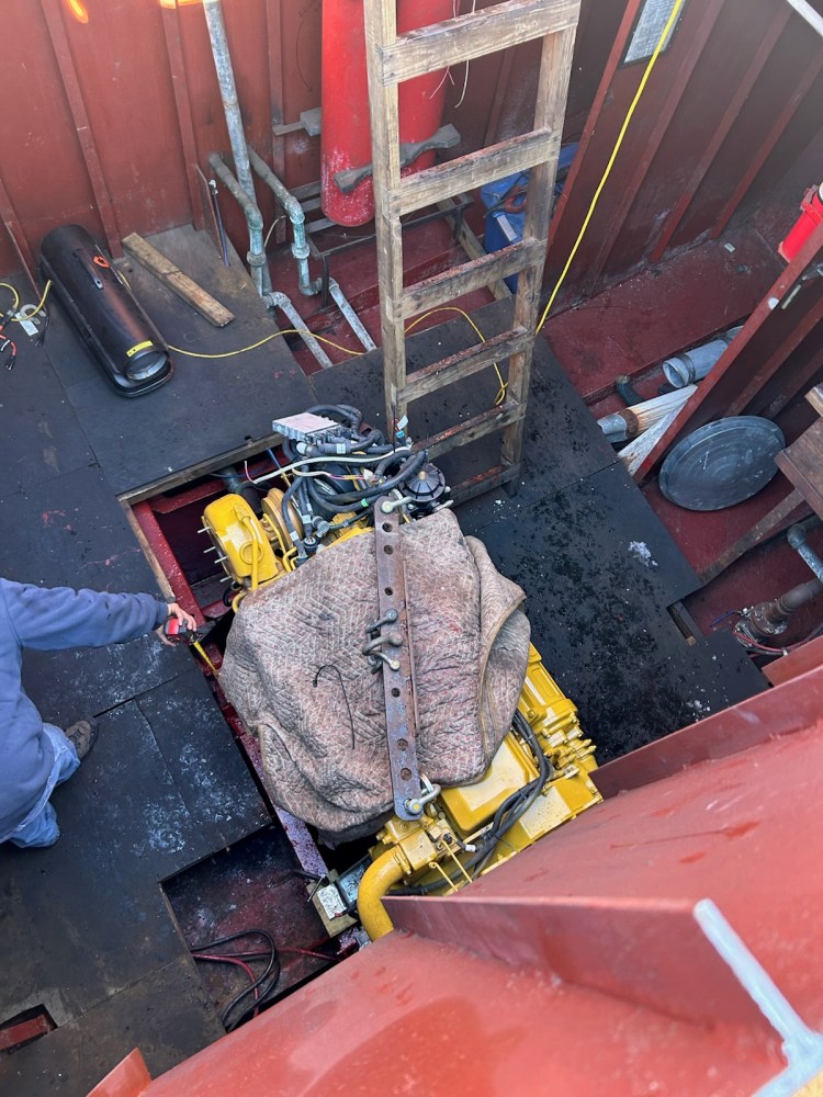 Person working near a covered engine in a wooden structure with a ladder.