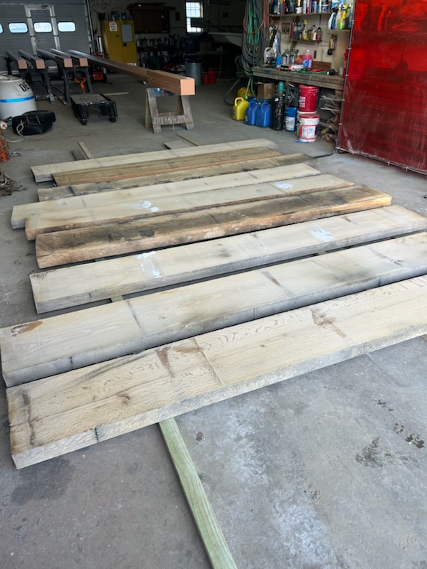 Wooden planks laid out on a garage floor with tools in the background.