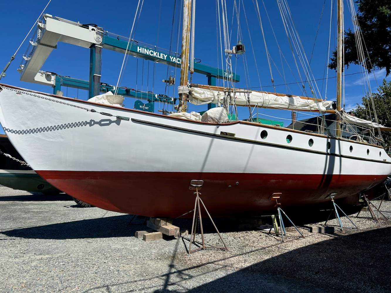 Sailboat on stands in a shipyard under clear blue sky.