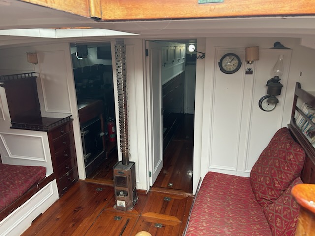 Cozy boat interior with wooden floors, cushioned seating, and nautical decor.