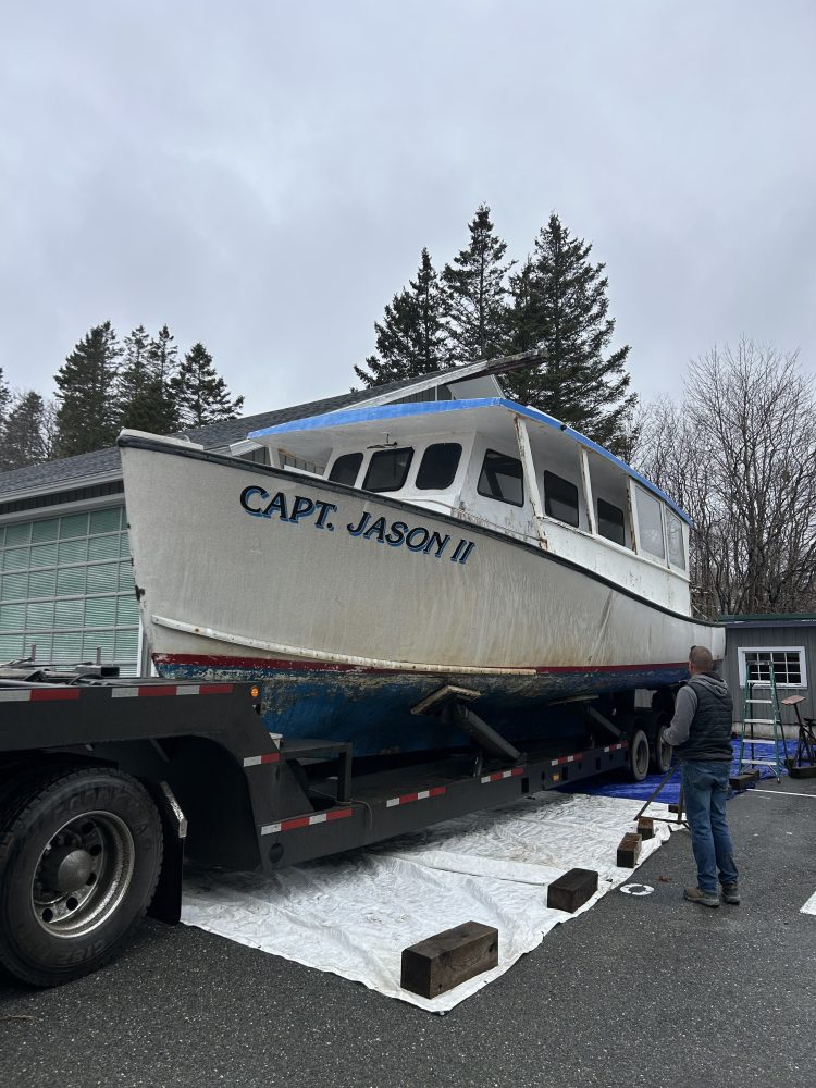 Boat named Capt. Jason II on a trailer in a driveway, with people nearby.