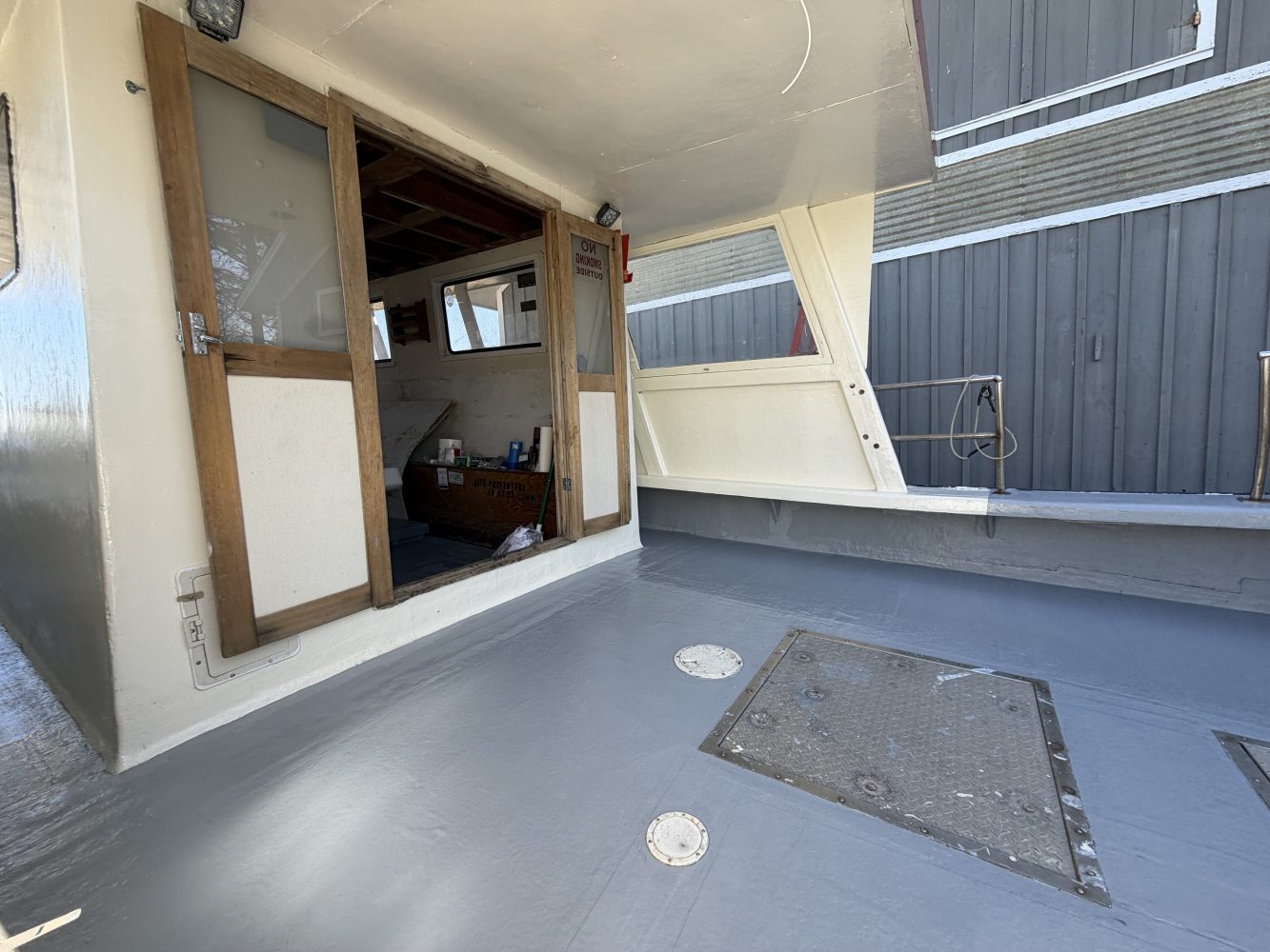 Inside view of a boat cabin with wooden elements and a ceiling hatch.
