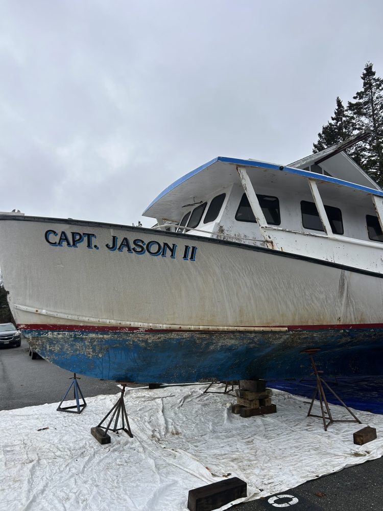 Boat named 'Capt. Jason II' on land with supports, cloudy day.