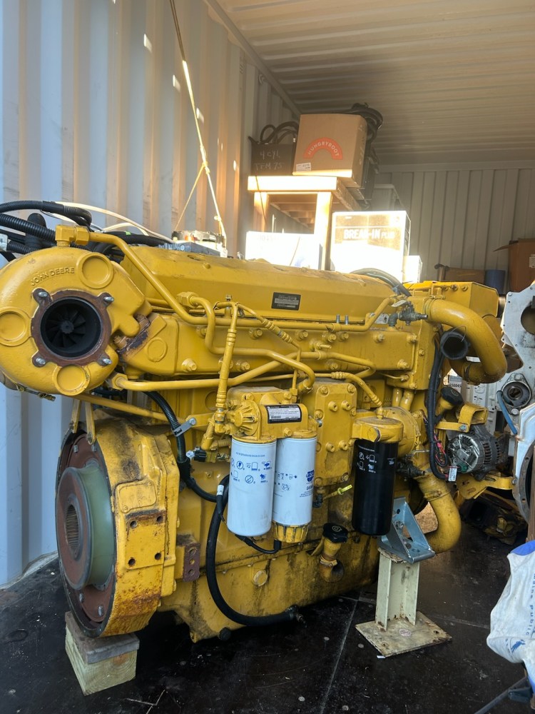 Yellow industrial engine inside a shipping container with various components.